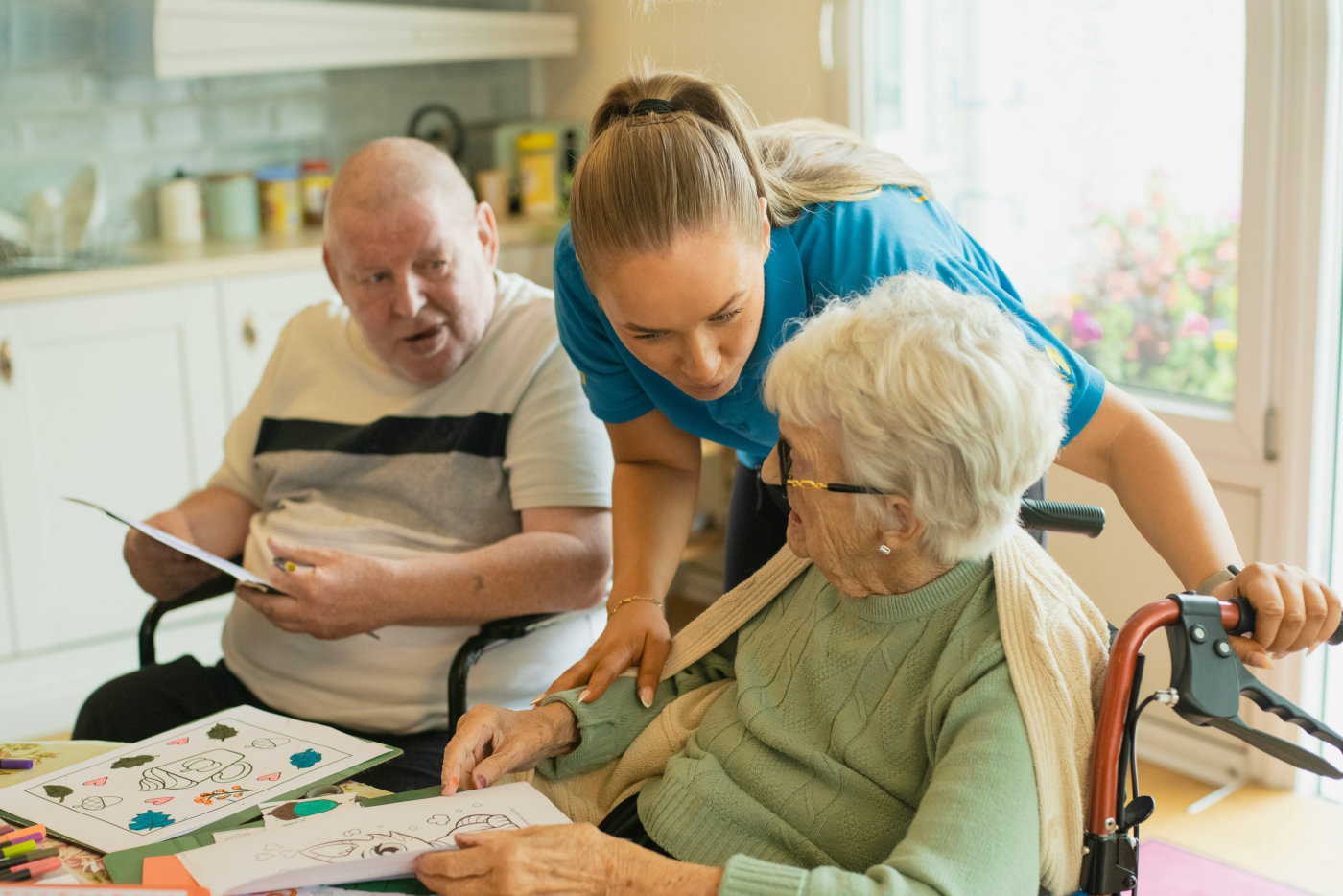 A woman stands beside a woman in a wheelchair, both appearing happy and engaged in conversation.